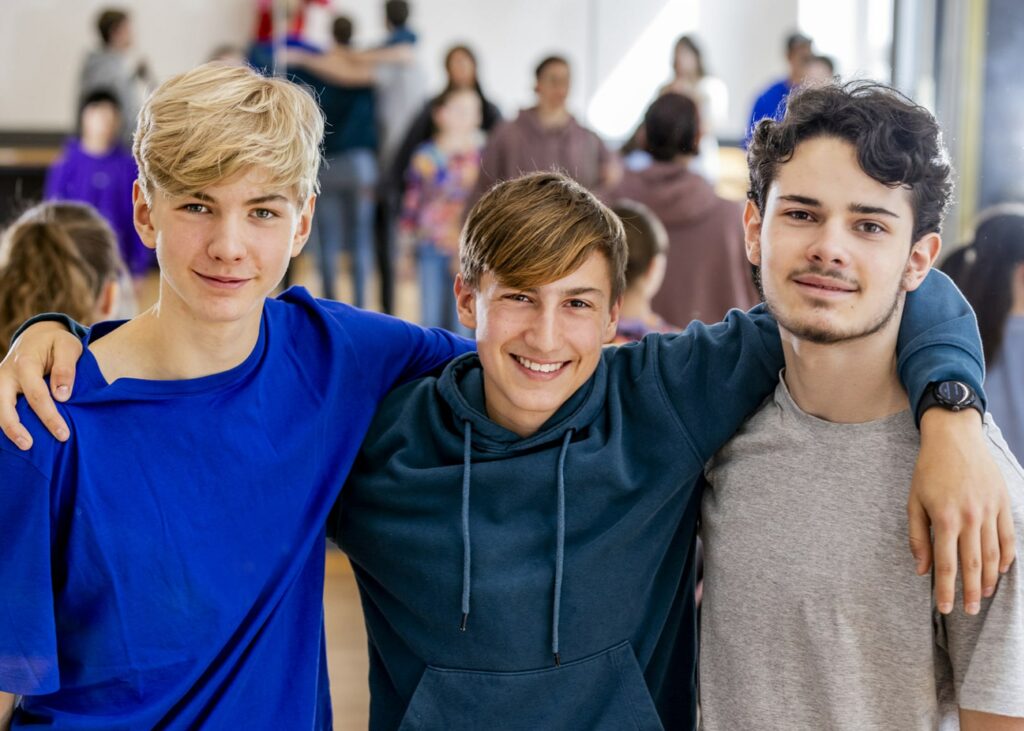 Foto dreier Schüler der HipHop AG der SABEL Schule, die Arm in Arm in die Kamera schauen. Sinnbild für den angedachten Bildungscampus Taufkirchen.